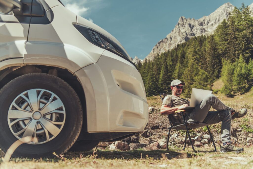 Man working from an RV outside on laptop