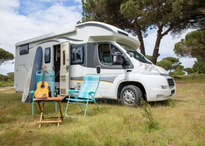 Image with RV and chairs set up outside on grass showing RV Living.