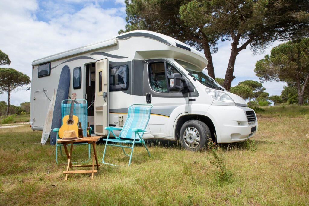 Image with RV and chairs set up outside on grass showing RV Living.